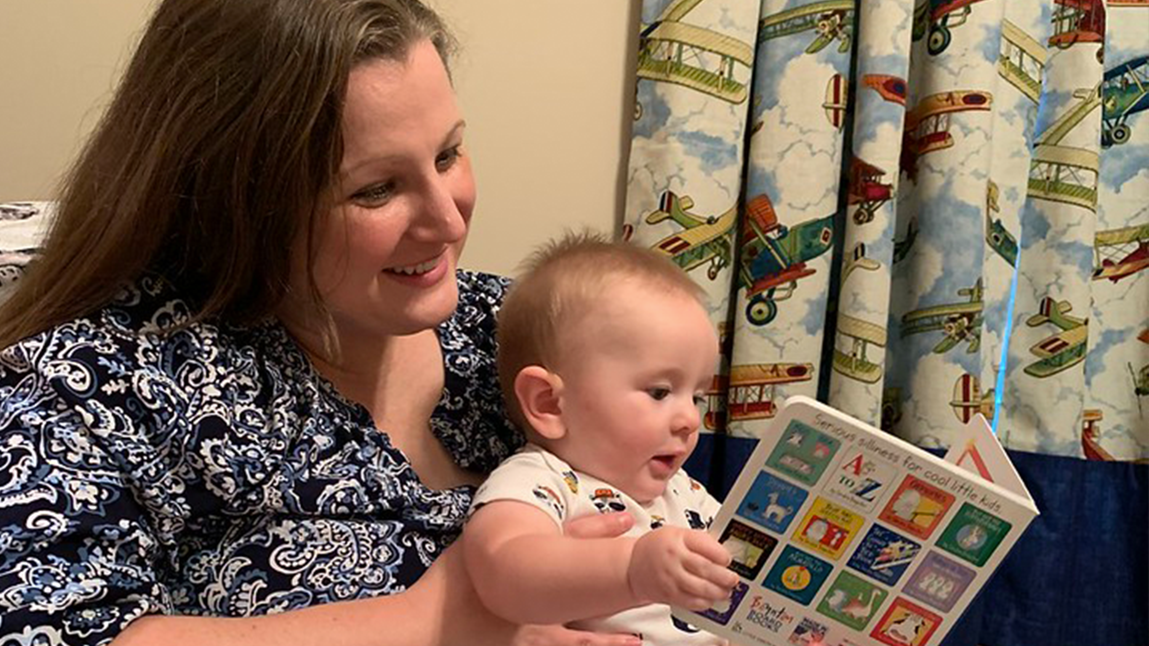 A woman reads a book to her infant